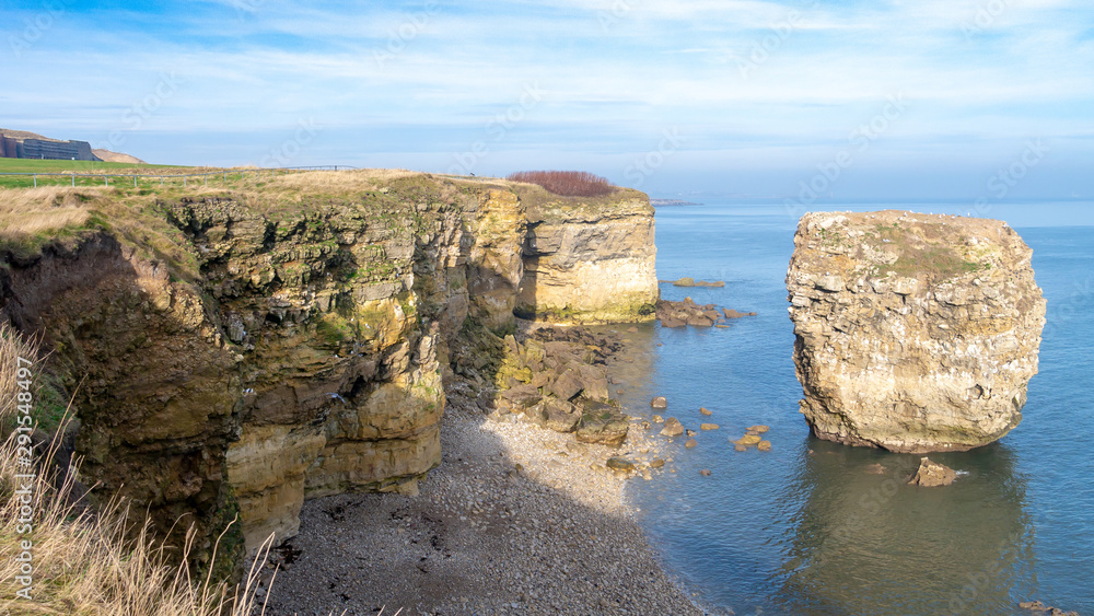 Scenic coastline image showing large eroded rock. on a calm North Sea.  Taken on the Leas cliff tops near Souter Lighthouse, Whitburn, Sunderland, Tyne and Wear, England UK.