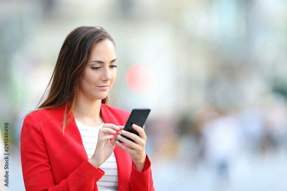 Serious woman in red using smart phone in the street Serious woman in red using smart phone in the street
