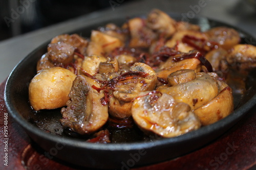  Sauteed mushrooms in butter with garlic and chili on iron and wood plate