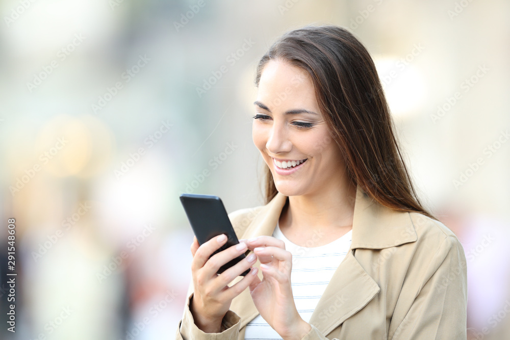 Happy casual lady using cell phone in the street