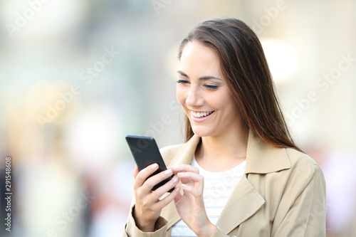 Happy casual lady using cell phone in the street