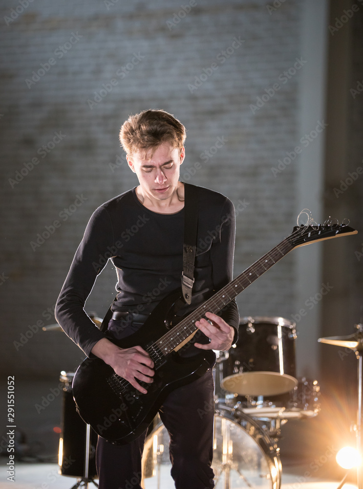 Fototapeta premium A musician man playing guitar and looking at his hands