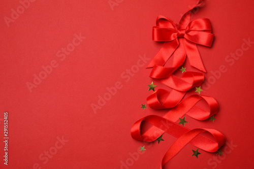 Red ribbon and glitter stars on red background  space for text