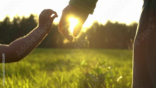 Cute toddler son holding his father hand on sunset. Happy family, love, support, togetherness.