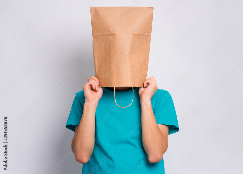 Portrait of teen boy with paper bag over head. Teenager cover head with