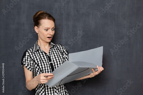 Portrait of shocked frightened girl looking at papers in folder