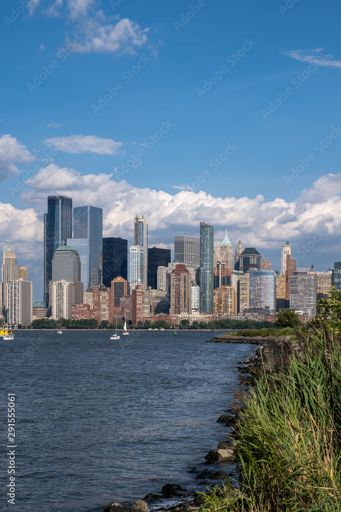 Fototapeta premium Lower Manhattan skyline with boat and ferry on Hudson river view from Liberty State Park in late summer