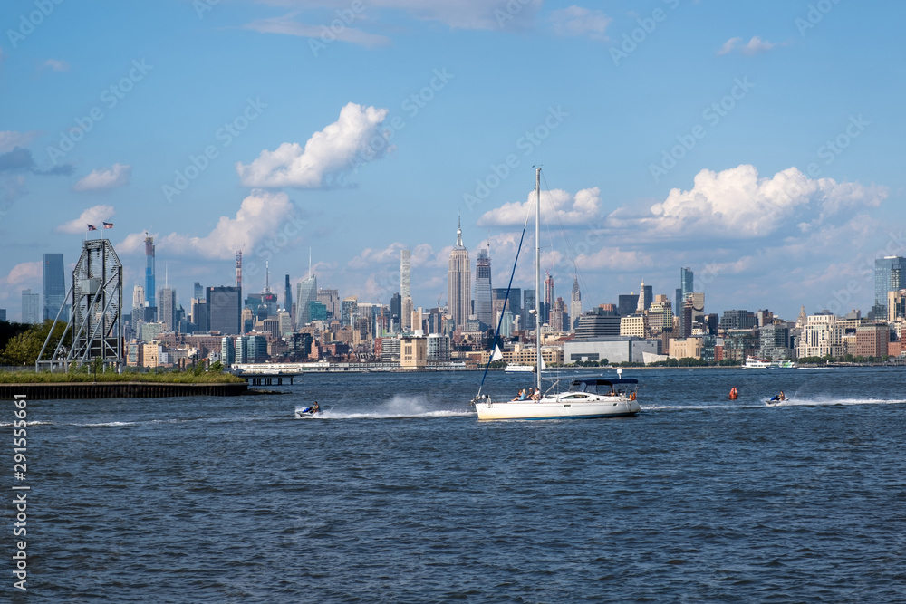 Lower Manhattan skyline with boat and ferry on Hudson river view from Liberty State Park in late summer