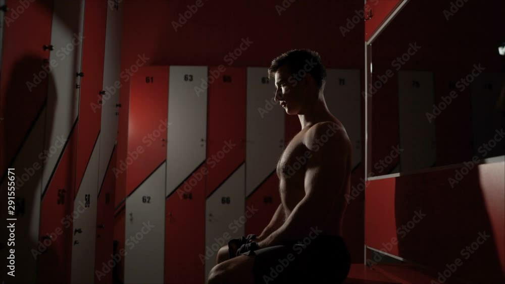 Sports man standing with towel and bag in the locker room at the gym ...