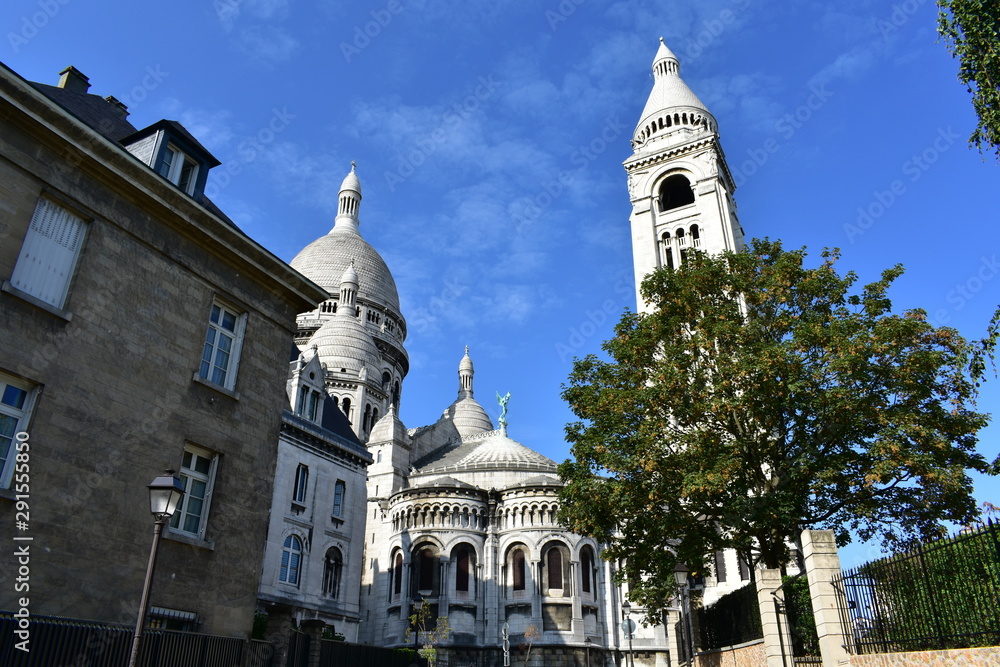 View of the Basilique du Sacre Coeur from nearby street with blue sky. Paris, France.