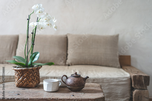 Wooden table with teapot, cup and orchid flower