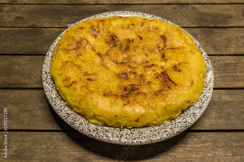 vegan Spanish omelette with potatoes onion and garlic, isolated in a wooden table photo