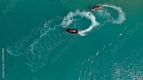 Aerial drone top down photo of 2 men operating jet ski watercraft cruising in high speed in tropical exotic lake