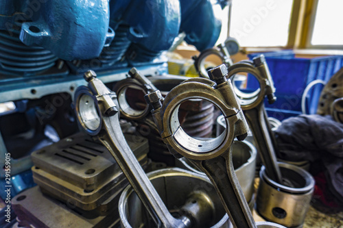 The connecting rod, piston and cylinder block in a disassembled condition in a car workshop.