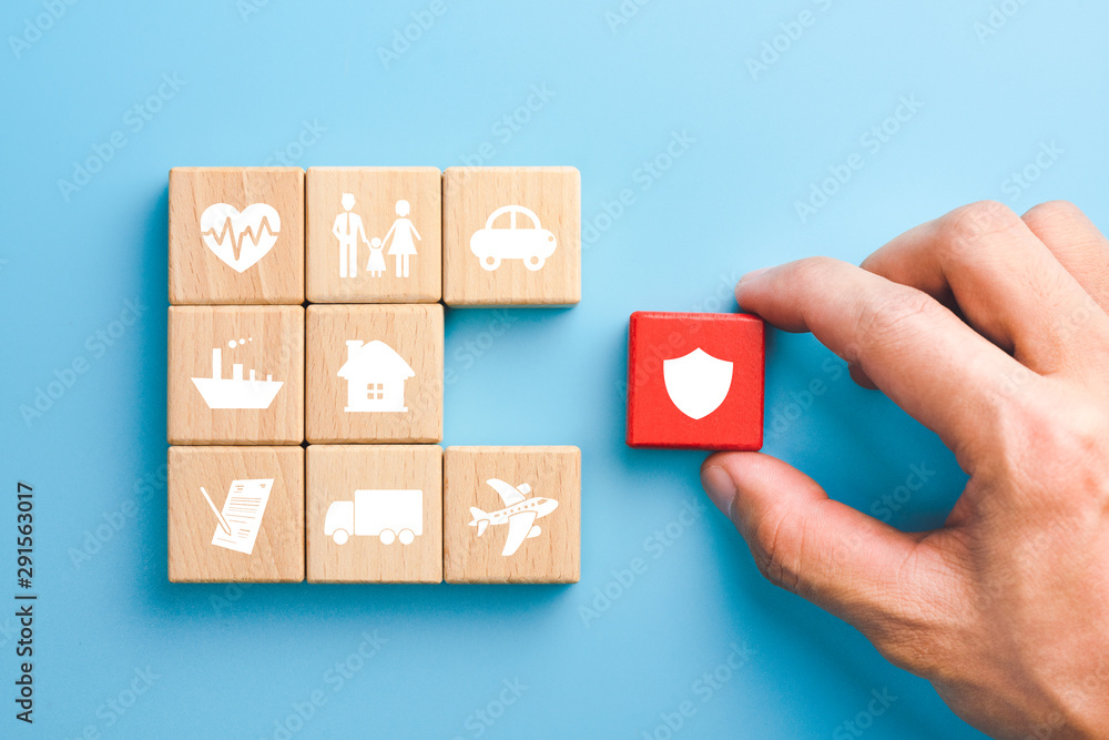 Hand holding red wooden blocks with insurance icons. family, life, car, travel, health and house insurance icons, blue background, Insurance concept - obrazy, fototapety, plakaty 