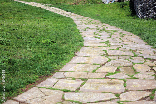 Stone paved ancient walkway on grass background.