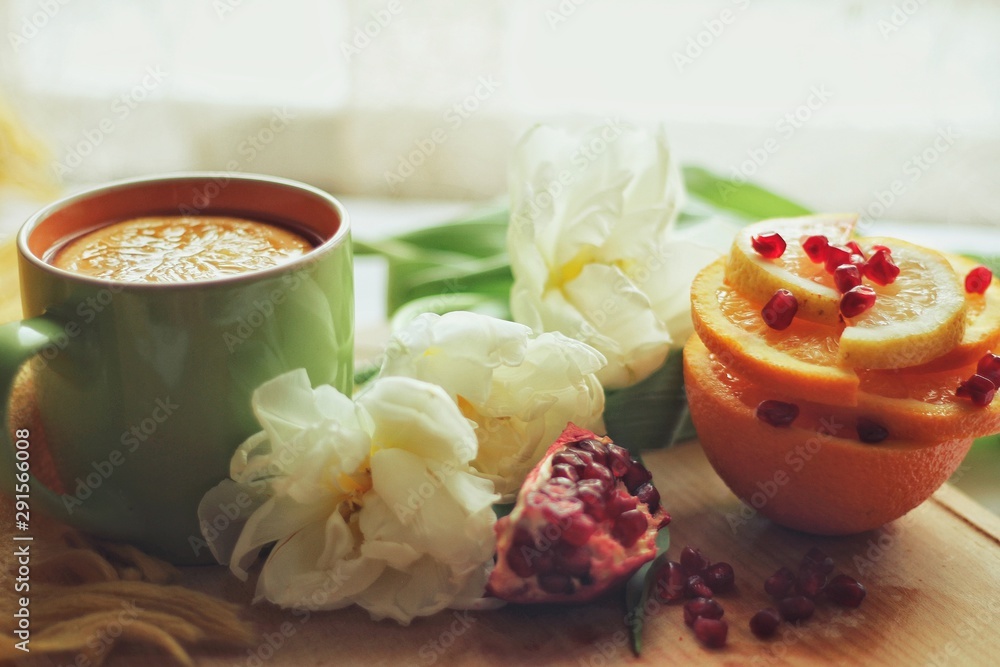 Tender white flower and cup of tea with pomegranate
