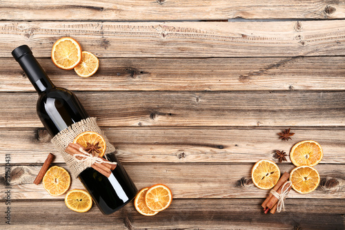 Dried citrus fruits with spices and bottle of wine on wooden table