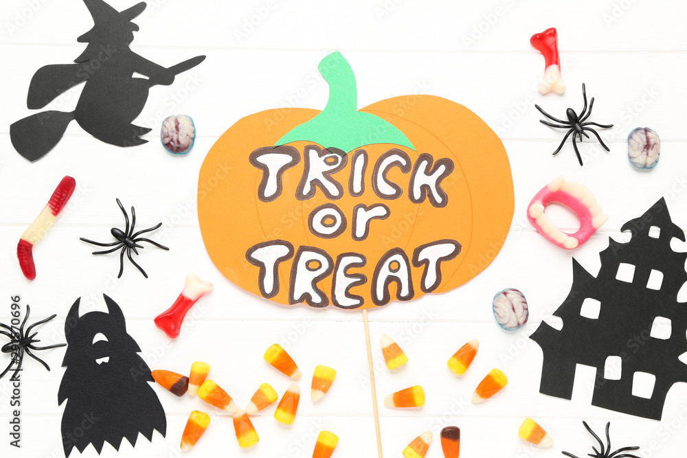 Obraz premium Text Trick or Treat with paper halloween decorations and candies on white background