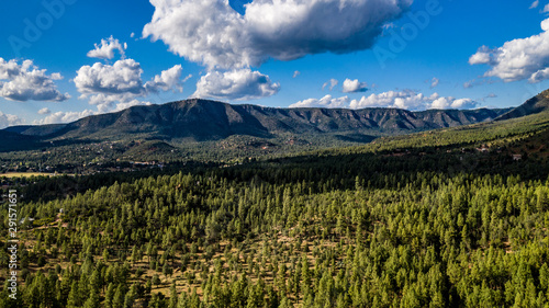 Aerial view of the Tonto National Forest from above the Pine Trailhead in Arizona with blue sky, white clouds and green ponderosa pines 
