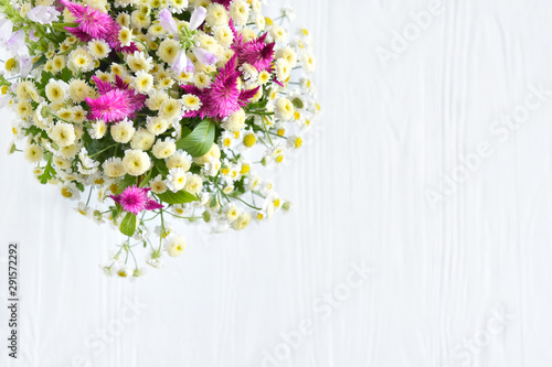 Gentle beautiful bouquet of wild flowers with white camomiles on blurred neutral background. Bunch of wildflowers on white backdrop. Romantic meadow flower with empty space for text © Tetiana Ivanova