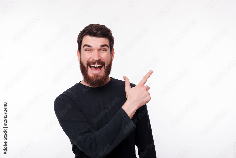 Cheerful bearded hipster man pointing away at copyspace Cheerful bearded hipster man pointing away at copyspace