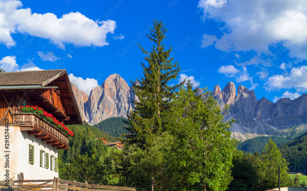 Val di Funes, South Tyrol / Italy. Traditional alpine house with flowered balcony with the Dolomites in the background