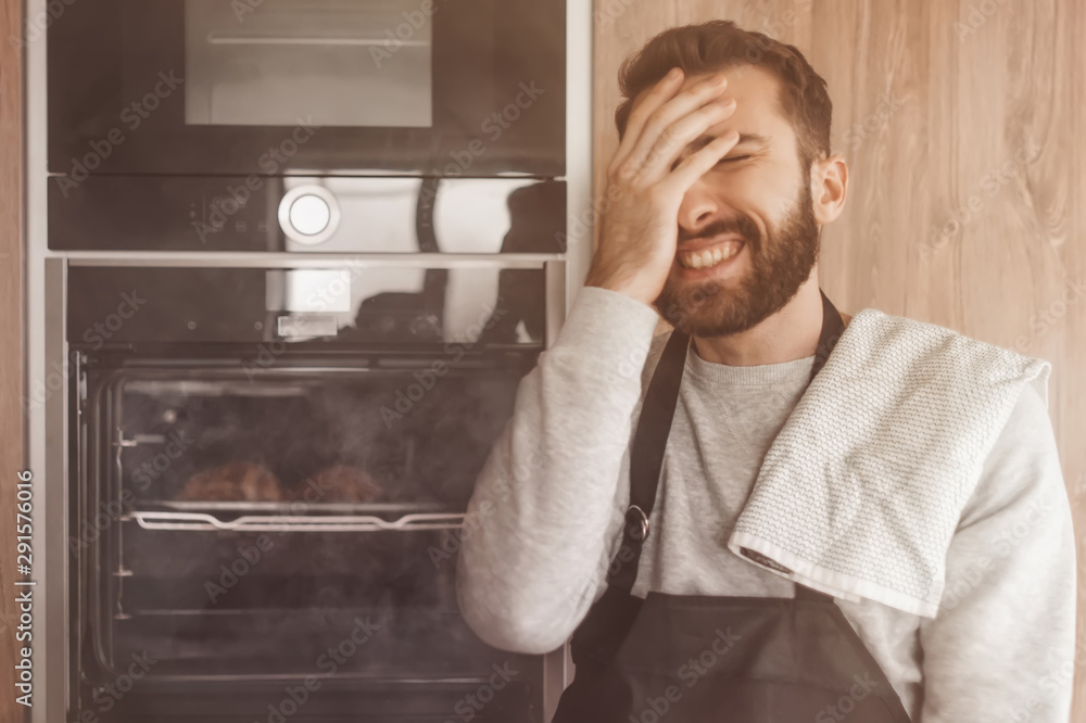 surprised man standing near the oven with burnt croissants. surprised man standing near the oven with burnt croissants.