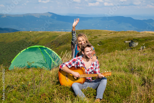 Travel couple enjoying wanderlast view, woman with arm up in excitement at mountain background. Happy family on vacation in mountains, hiking and looking at beautiful view. Couple in love. photo