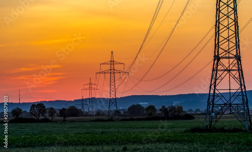 High voltage electricity pylons and transmission power lines on the blue sky background.