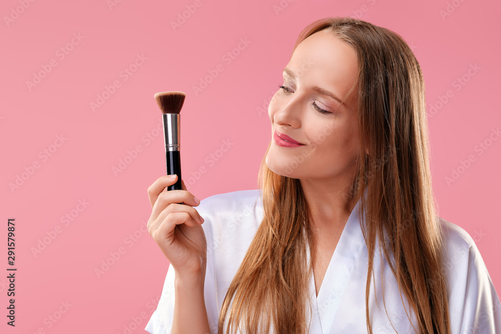 Happy smiling woman looking at blush and powder brush Happy smiling woman looking at blush and powder brush