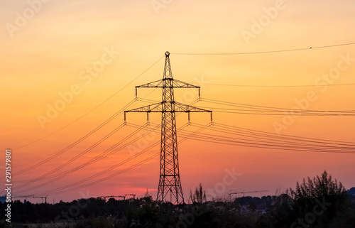 High voltage electricity pylons and transmission power lines on the blue sky background.