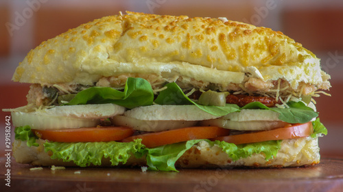 Long sandwich with chicken, lettuce, tomato and olives close up