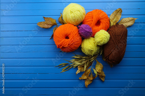 Composition with yarn balls and autumn leaves on wooden background