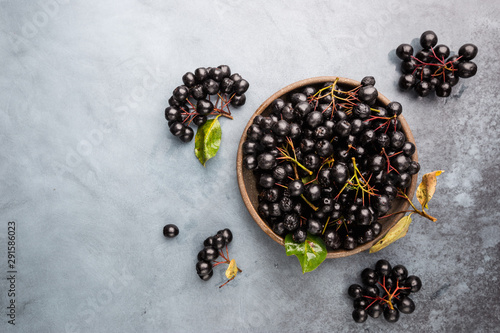 Bowl with freshly picked homegrown aronia berries. Aronia, commonly known as the chokeberry, with leaves, top view photo