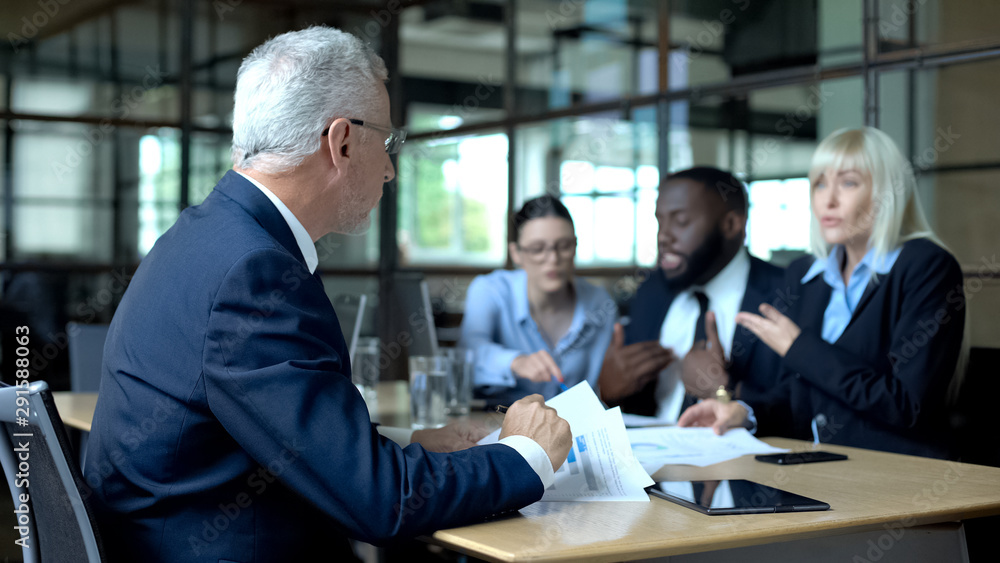 Senior businessman looking at colleagues arguing and shouting, stressful work Senior businessman looking at colleagues arguing and shouting, stressful work