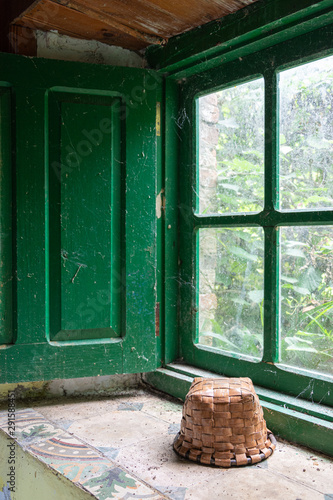 Detail of green window sill with a basket  in an abandoned house and vegetation outside in Cantabria  Spain  Europe