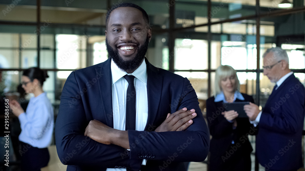 Fototapeta premium Smiling african businessman with folded arms, office work, corporate success