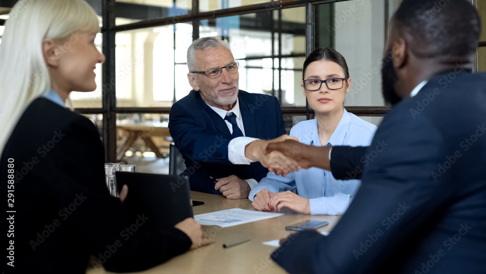 Business people shaking hands in office approving deal, discussing agreement Business people shaking hands in office approving deal, discussing agreement