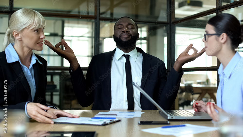 Businessman meditating in office, tired of female colleagues conflict at work Businessman meditating in office, tired of female colleagues conflict at work