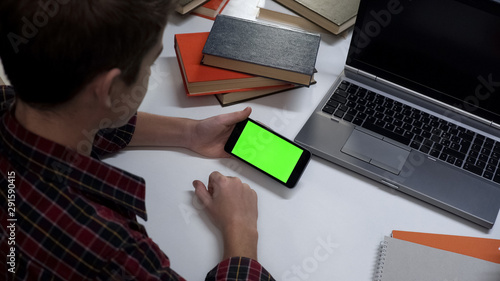 Teenager with green screen smartphone hands watching online video, application photo