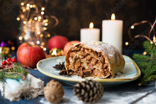 Christmas and New year dessert. Apple strudel with holiday lights.