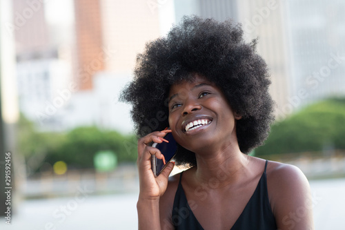 A pretty African american business woman talking on a cell phone at office building in the city