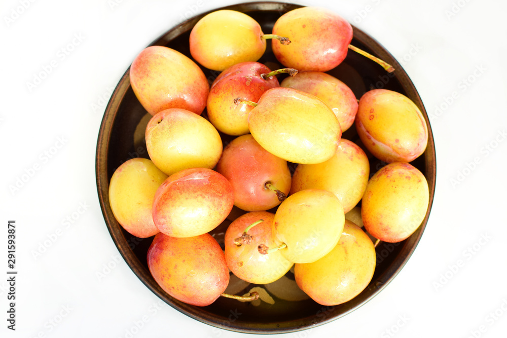 Yellow and red plums on a ceramic plate. Close-up Yellow and red plums on a ceramic plate. Close-up