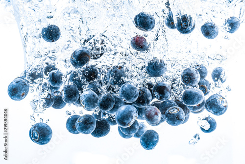 Fresh blueberries falling in water on white background. Fruits splashing into clear water.