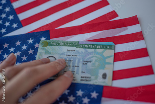 Permanent Resident Green card  of United states of America on flag of USA. Above close up view.