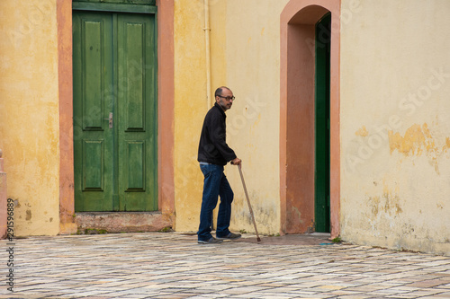 Disabled man walks with walking stick and difficulty on the street © Rogerio