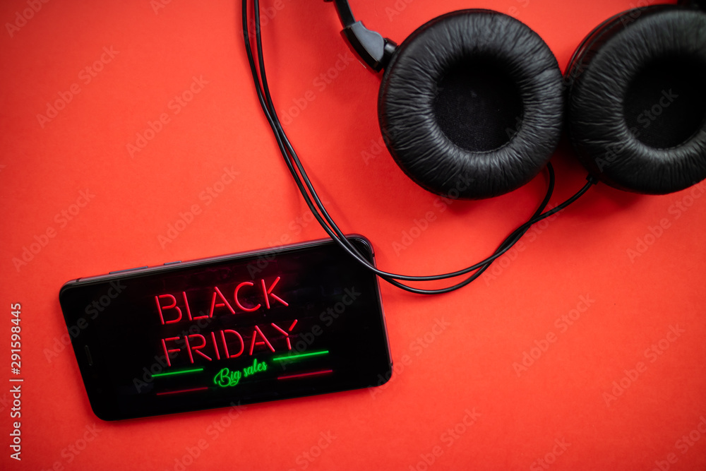 Mobile phone with Black Friday advertisement neon effect and headphones on  red background. Black Friday concept. Stock-Foto | Adobe Stock