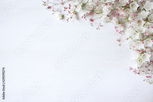 Floral wooden background for congratulations with flowers of white bells and pink gypsophila.