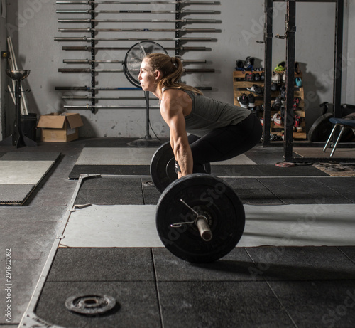 Photography Strong female weight lifter getting ready to lift heavy barbell in grungy gym
